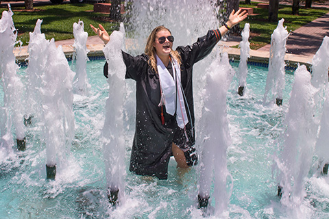 Student celebrating graduation in a fountain